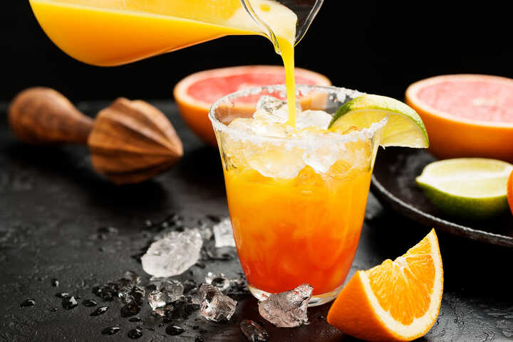 Alcohol free fruit juice punch being poured into a glass with ice. 