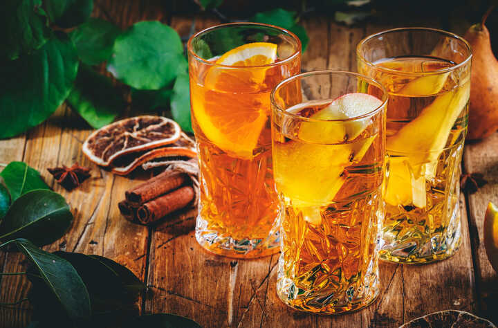 Warm spiced apple in glasses with sliced orange to garnish
